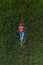 Aerial view of female farmer laying in green wheat field and resting, top down drone pov