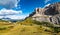 Aerial view of female hiker heading to Gardena Pass and Sass dla Luesa dolomite tower, Trentino Alto Adige, Italy. Alpine meadows