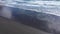 Aerial view of a female traveler relaxing on Atlantic ocean coast. Sea waves washing black sandy beach. Hofn, Iceland