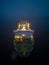 Aerial view of a ferryboat navigating through foggy conditions at night on the sea.