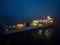 Aerial view of a ferryboat navigating through foggy conditions at night on the sea.