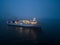 Aerial view of a ferryboat navigating through foggy conditions at night on the sea.