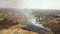 Aerial view of a field with dry grass set on fire with orange flames and high column of smoke.