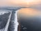 Aerial view at the Finland gulf with the Baltic sea, road passing along seaside. Winter season with snowy trees and sandy beach,