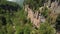 Aerial view of the flight of the camera over a deep rocky gorge with high cliffs and a dense forest and a river flowing