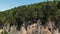 Aerial view of the flight of the camera over a deep rocky gorge with high cliffs and a dense forest. Wildlife on a sunny