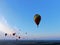 Aerial view flights in large balloons above the forest and field at sunset. Balloon festival. Beautiful landscape at sunset