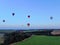 Aerial view flights in large balloons above the forest and field at sunset. Balloon festival. Beautiful landscape at sunset