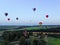 Aerial view flights in large balloons above the forest and field at sunset. Balloon festival. Beautiful landscape at sunset