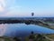 Aerial view flights in large balloons above the forest and field at sunset. Balloon festival. Beautiful landscape at sunset