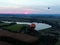 Aerial view flights in large balloons above the forest and field at sunset. Balloon festival. Beautiful landscape at sunset