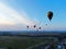 Aerial view flights in large balloons above the forest and field at sunset. Balloon festival. Beautiful landscape at sunset