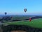 Aerial view flights in large balloons above the forest and field at sunset. Balloon festival. Beautiful landscape at sunset