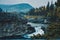 Aerial view of flowing waterfall from rocks surrounded by autumn dense trees