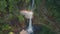 Aerial view fly orbiting over Kapas Biru Waterfall with rainbow, Java, Indonesia