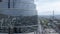 aerial view, flyby fragment of a skyscraper tower made of blue glass close-up on the background of both the city