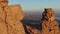 Aerial view. Flying along the Rocks Flooded by the Sunset on the Background of the Valley and Silhouettes of Mountains