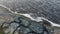 Aerial view, flying over coastline during a storm. Top view on rocky shore and sea waves with foam