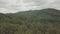 Aerial view flying over green tree tops of dense forest and over the mountains