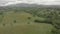 Aerial view - Flying over hilly landscape with green meadows and valleys with woods and hills