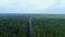 Aerial view flying over road. Green forest. Drone shot from above.