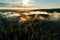 Aerial view of a foggy forest with a golden sunrise in the background