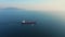 Aerial view following the ultra large cargo ship at sea leaves port at sunset