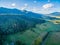 Aerial view of forested mountains, meadows, pastures, and rural road.