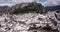 Aerial view of fortified castle on top of crag and white houses at bottom of hill in Zahara de la Sierra on background