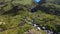 Aerial view of four tourists with trekking poles approaching a beautiful mountain waterfall.