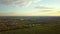 Aerial view of fresh garden trees, pathed plowed farm fields and distant town houses in spring.