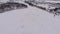 Aerial view of frozen lake, surrounded by forest and cottage village.