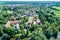 Aerial view of a German village with a small forest, a pond and a moated castle in the foreground