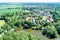 Aerial view of a German village with a small forest, a pond and a moated castle in the foreground