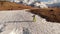 Aerial view girl athlete skier climbs on foot along the slope with a snowboard on his shoulders next to the kicker at a