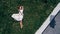 Aerial View of The Girl that Lies on a Green Lawn in a White Dress
