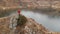 Aerial view of a girl sits down on a rock on the shore of a lake. Travel videos