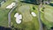 Aerial view of golf course green with flag, bunkers, golf cart pathways
