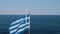 Aerial View of Greek National Flag Waving on Coast of Aegean Sea