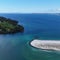 Aerial view of a green coastline against the sea waves