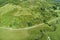 Aerial view of green countryside road on a sunny day. Breathtaking nature landscape of an empty roadway winding through