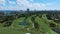 Aerial view of green golf course near residential buildings in summer. Picturesque lakes, tropical palm trees in La