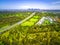 Aerial view of green parkland, Melbourne Polytechnic, and Melbourne CBD skyscrapers in the distance on summer day.