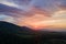 Aerial view of green pine forest with dark spruce trees covering mountain hills at sunset. Nothern woodland scenery from