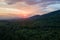 Aerial view of green pine forest with dark spruce trees covering mountain hills at sunset. Nothern woodland scenery from