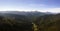 Aerial view of green pine forest with dark spruce trees covering mountain hills at sunset. Nothern woodland scenery from