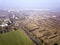 Aerial view of green and plowed fields and city suburbs on sunny dawn. Drone photography