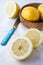 Aerial view of half lemons, blue knife and wooden bowl, on white dishcloth, selective focus,