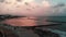 Aerial view of happy relaxed tourists walking along promenade and enjoying vacation near mediterranean sea at the sunset