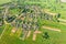 Aerial view from the height of the village with houses and streets, plowed fields in the summer